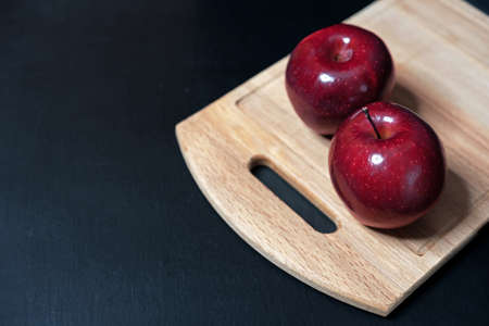Two red apples on a wooden cutting board.の写真素材