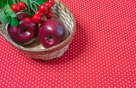 Red apples and red berries in a wicker basket.の写真素材