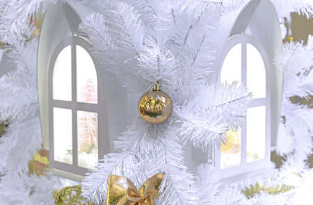 Yellow Christmas ball on a white Christmas tree near the glowing windows.の写真素材