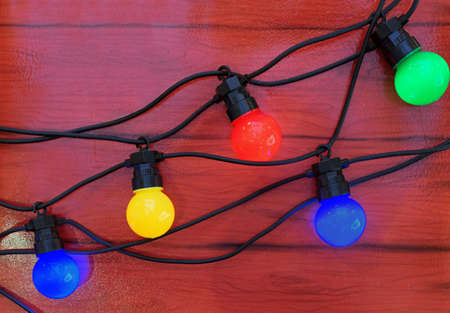 Christmas garland with multi-colored light bulbs on a brown background.の写真素材