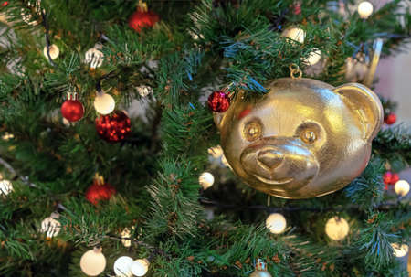 Christmas toy in the shape of a golden bear on a Christmas tree with a garland.の写真素材