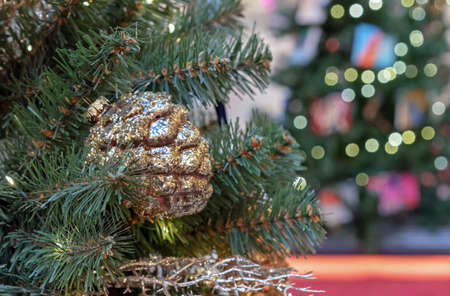 Pine cone with golden sparkles - christmas toy on a Christmas tree.の写真素材