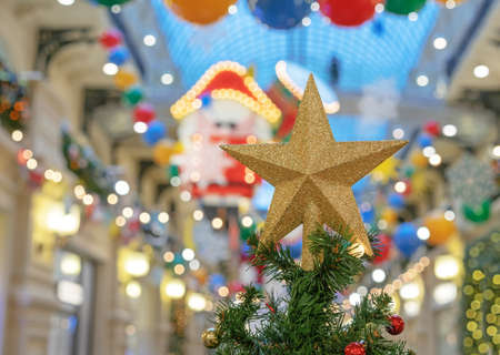 Gold glittering star on top of christmas tree on colorful bokeh background.の写真素材