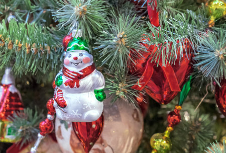 Cheerful snowman with a red scarf and in a green hat on the Christmas tree.の写真素材