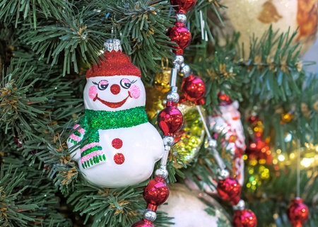 Cheerful snowman with a green scarf and in a red hat on the Christmas tree.の写真素材