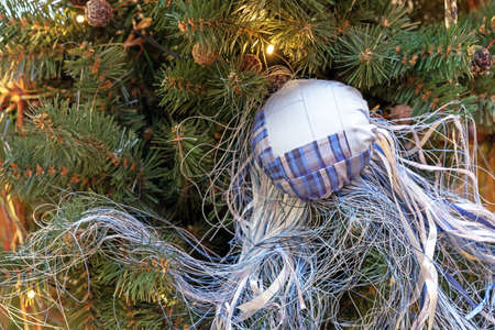 Fabric Christmas ball with many threads hangs on a Christmas tree with a garland.の写真素材