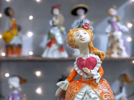 Ceramic doll in an antique lush dress and with heart in hand.の写真素材