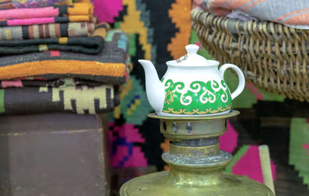 Ceramic teapot with green ethnic ornament among antiques.の写真素材