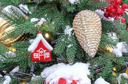 Red Christmas small hut and golden pine cone on the Christmas tree.