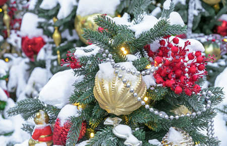 Red berries and a yellow faceted Christmas ball on the Christmas tree.の写真素材
