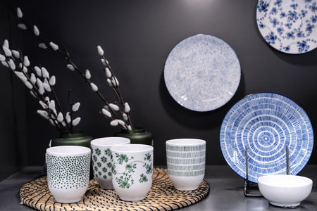 Ceramic cups with green ornaments and vases with willow branches on the kitchen shelf.の写真素材