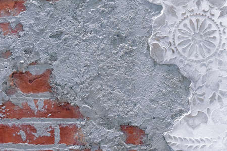 Damaged plaster on brick wall background. Brickwork under crumbling texture concrete surface.の写真素材