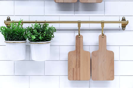 Wooden cutting boards and pots of flowers on the hooks of a kitchen metal rail.の写真素材