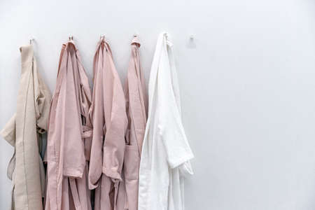 White and beige bathrobes on hooks in the bathroom. home wear.の写真素材
