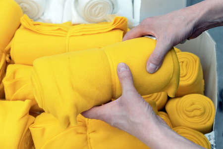 Yellow plaid in the hands of a man. Showcase with soft blankets.の写真素材