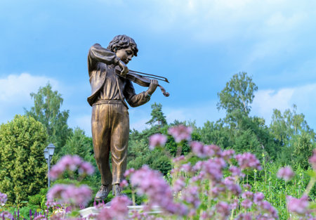 MOSCOW, RUSSIA - July 06, 2022: Bronze sculpture "Boy playing the violin" in the summer garden.のeditorial素材