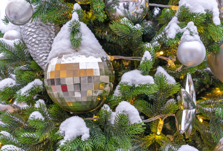 Golden Christmas ball with square edges on a snowy Christmas tree.の写真素材