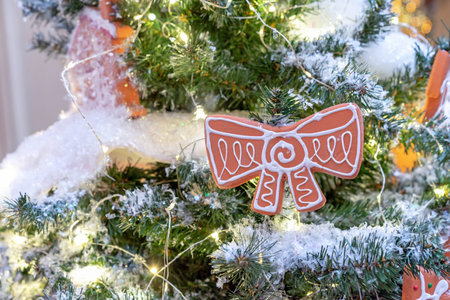 Christmas gingerbread with icing in the shape of a bow on the Christmas tree with a garland.