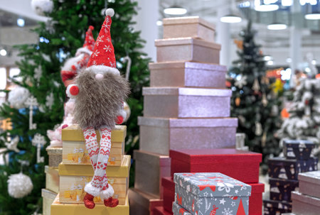 Christmas long-legged gnome in a suit with a scandinavian ornament on the background of boxes with gifts.の写真素材