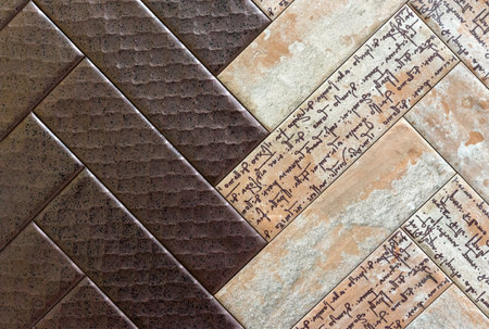 Brown and beige ceramic tiles with letters laid out in a herringbone pattern.の写真素材