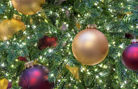 Yellow and burgundy matte Christmas balls on Christmas tree with a garland.の写真素材