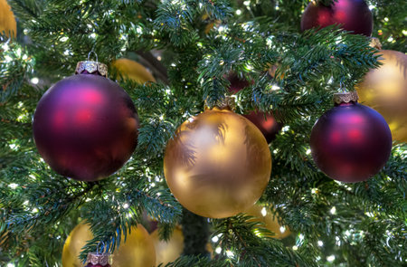 Yellow and burgundy matte Christmas balls on Christmas tree with a garland.の写真素材