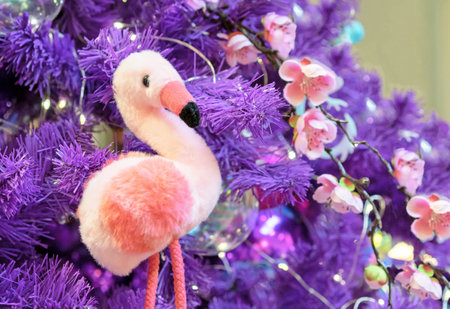 Soft toy pink flamingo on a violet Christmas tree.の写真素材