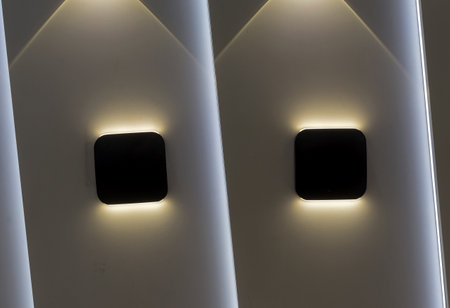 Two wall lights with symmetrical highlights on the wall.の写真素材
