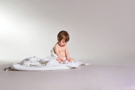 Charming girl sitting on white blanket, space for textの写真素材