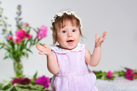Little girl in a pink dress sitting with a bouquet of pink flowersの写真素材