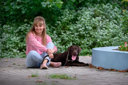 blonde girl smiling with dog Labrador. Labrador lying nextの写真素材