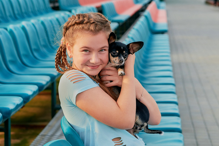 smiling girl relaxing with dog. girl with her pet on the seats of the stadiumの写真素材