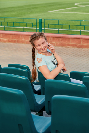 the girl on the seat in the stands.A young bright girl loves sports.の写真素材
