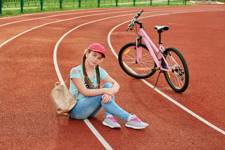 Teenage girl relaxing on a stadium.Teenage girl relax with the bike.の写真素材