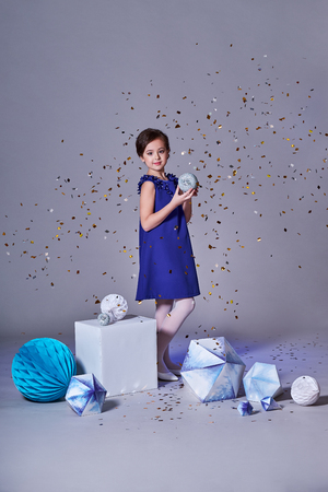 One beautiful child girl with confetti in blue dress fashion. Charming teenager girl in studio,makeup.Happy holidays.の写真素材