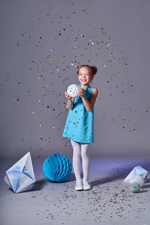 Cute baby girl in blue dress pretty model enjoying holiday and throwing confetti. Fashion kid christmas photos.の写真素材