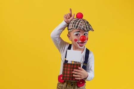 Cute little boy clown in a costume, makeup.Funny kid clown fooling.Young child shows expression face joy,smile,cheerful.1 April fools day celebration.Concept holiday, birthday,laughter,jokes,party.の写真素材