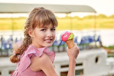 Happy smiling girl holding sweet ice cream. Portrait child teenager 11 years, elegant lady, outdoors summer. Caucasian face, clean skin. Delicious cold dessert in a waffle horn.の写真素材