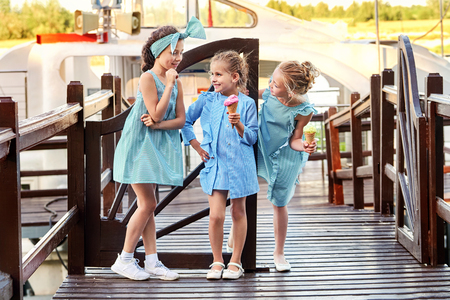 Group 3 fashion lady kids in elegant striped dresses in marine style.Little girls cool,summer clothes outdoors.Designer childrens collection.Friendship,smile,resting together,standing on bridge.の写真素材