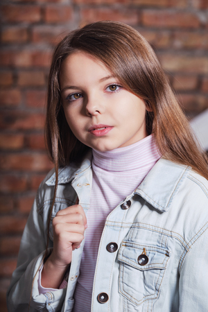 Portrait little fashion kid. Childrens fashion concept. Stylish hipster girl looks confident, defiant. Beautiful face caucasian child wearing denim jacket,jeans.の写真素材