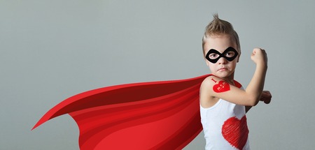 Funny strong child raising hand in success gesture. Little cool boy superhero loves mom, shows heart.の写真素材
