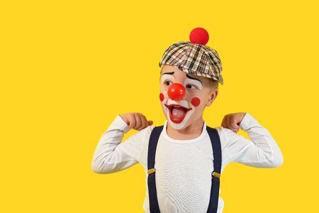 Portrait funny child.Cheerful boy,costume clown,red nose,makeup.Emotional face little comic kid.Happy baby isolated yellow background.1 April fools day celebration. concept birthday, holiday, humor.の写真素材