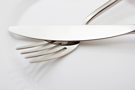 Fork and knife on white empty plateの写真素材
