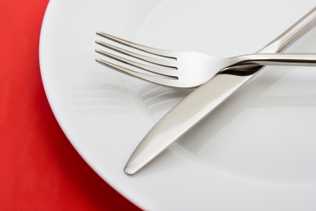 White empty plate with fork and knife on redの写真素材