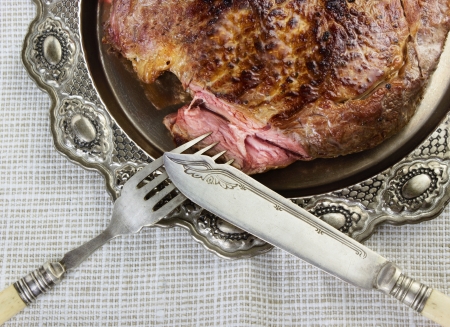 Steak on silver plate with fork and knifeの写真素材