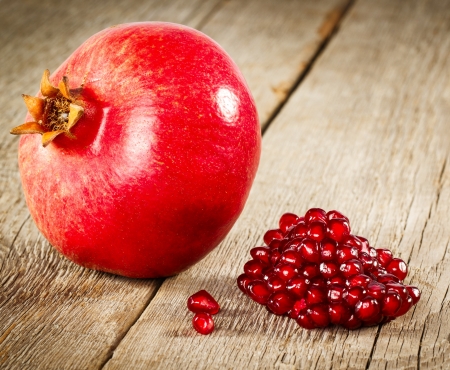 Whole pomegranate with seeds on wooden backgroundの写真素材