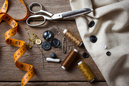 Sewing accessories: scissors, needle, thimble on wooden tableの写真素材