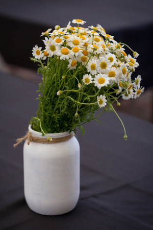 Bouquet of daisy chamomile flowers in concrete pot on black tableの写真素材