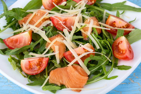 Close up view of fresh salmon salad with cherry tomatoes and sheese on blue wooden backgroundの写真素材