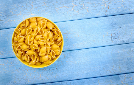 Raw yellow pasta in plate on blue wooden plank backgroundの写真素材